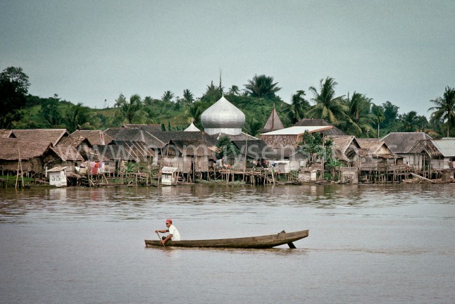 Pueblo típico de la etnia kutai de la parte baja del río Mahakam. La gente aquí vivía de la agricultura y de la pesca. Al acercarse en barco, lo primero que se distinguía era la cúpula de la mezquita. Las cajas de madera marcadas con números son retretes flotantes.
